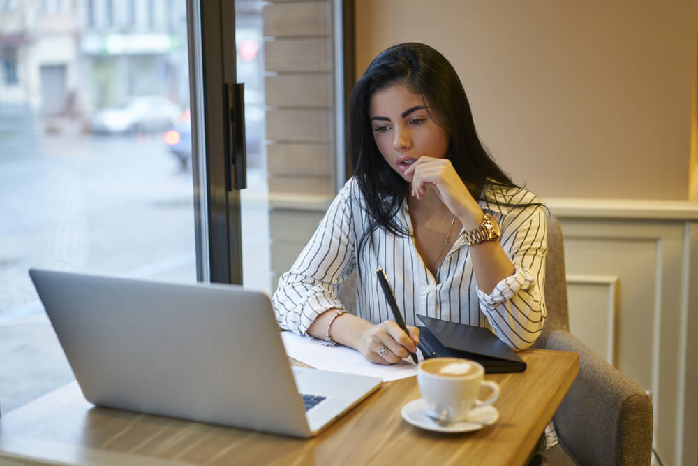 Female property manager working at her laptop in a coffee shop