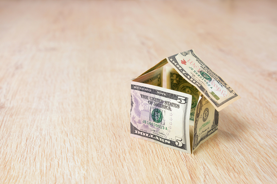 Money house made of dollar bills on wooden background